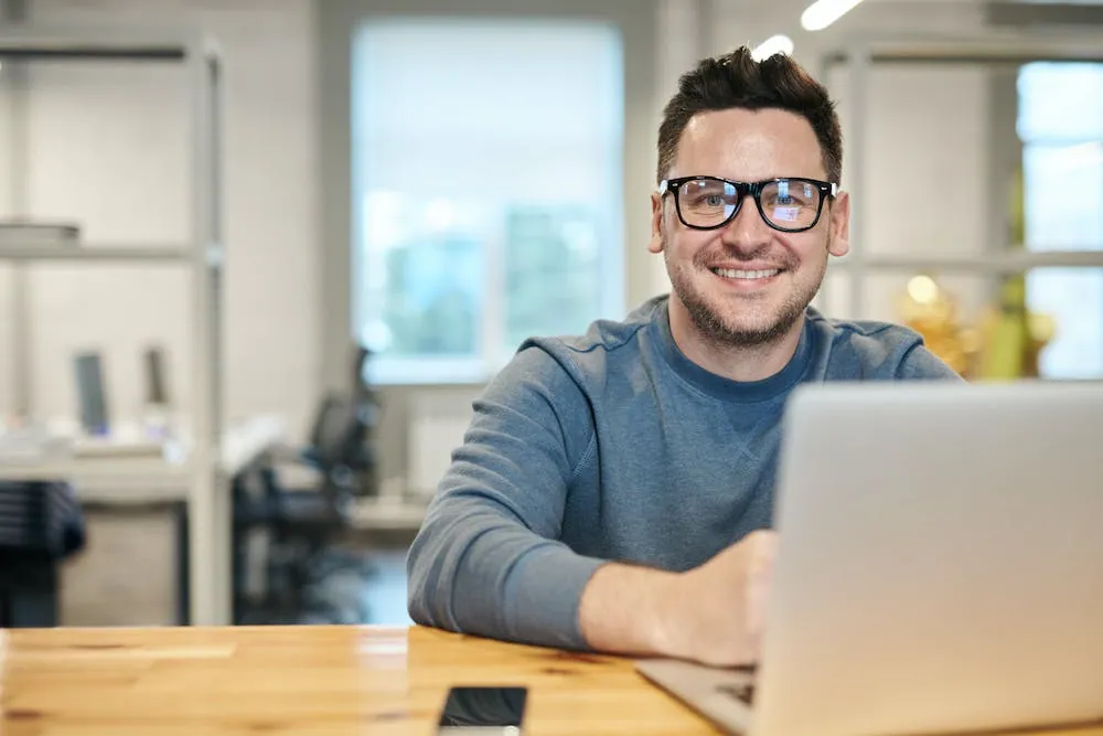 man glasses man in long sleeve shirt smiling with glasses looking at you